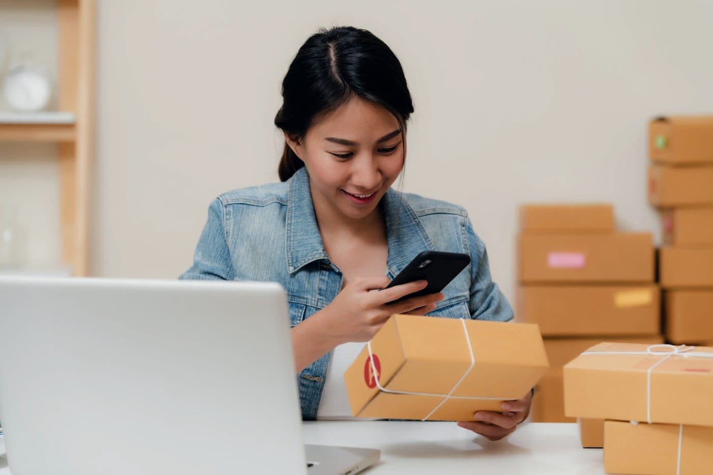 A small business owner working at a laptop beside stock and parcels