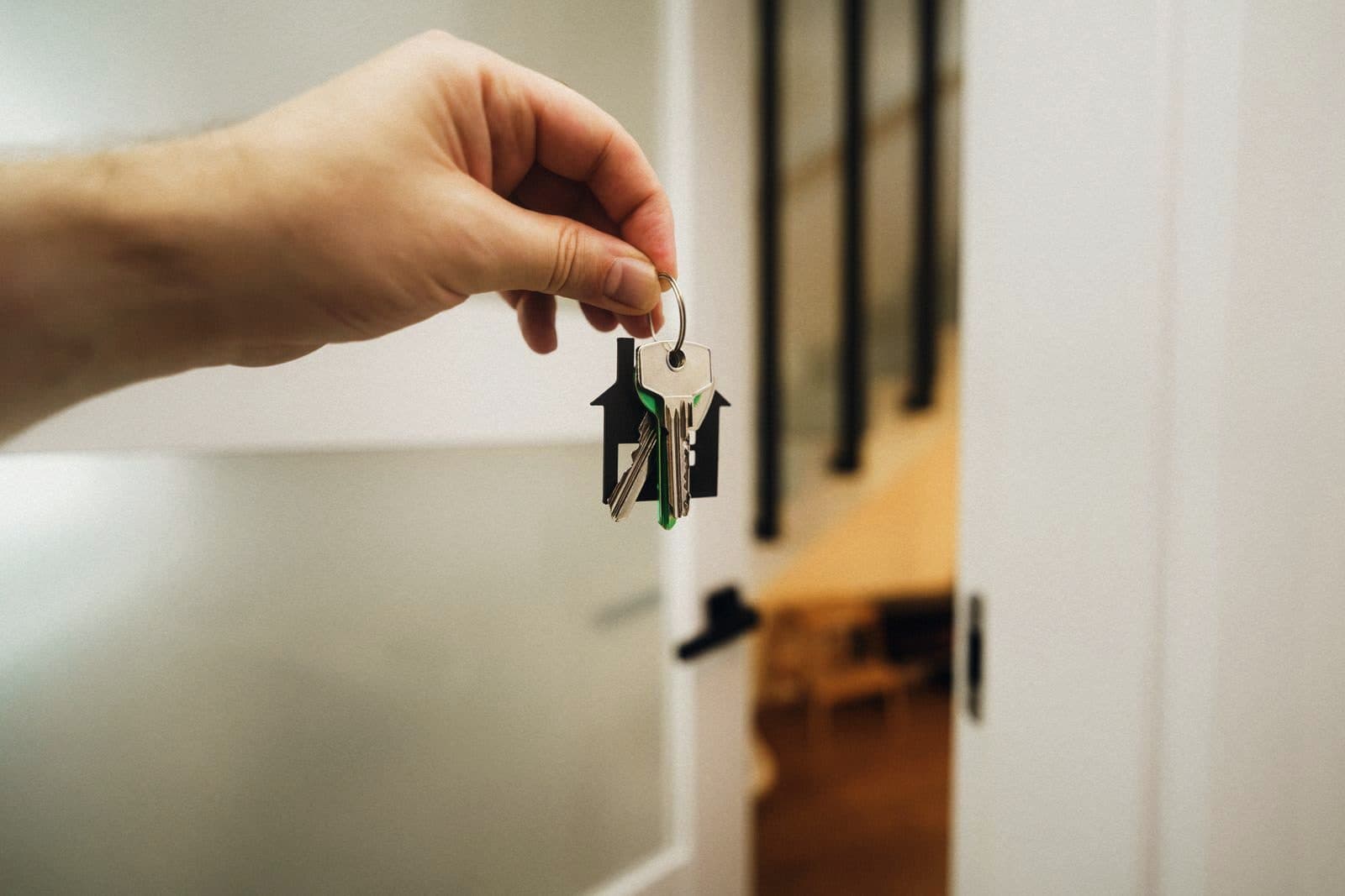 A hand holding house keys in the doorway of a property